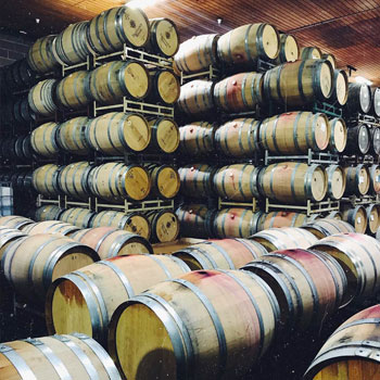 An interior shot of the barrel room at Trentadue Winery in Alexander Valley. Red wine-stained oak barrels are stacked from floor to ceiling.