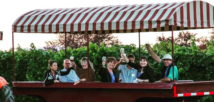 A wide angle view of a gondola wine car at Trentadue Winery carrying a group of 7 people. They are smiling and looking at the camera with raised wine glasses.
