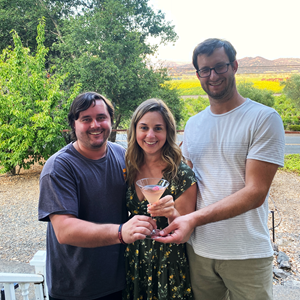 three cousins holding a single cocktail in front of a mountain background